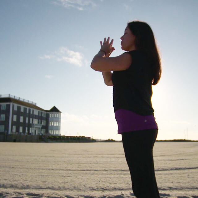 A woman meditating on a beach.