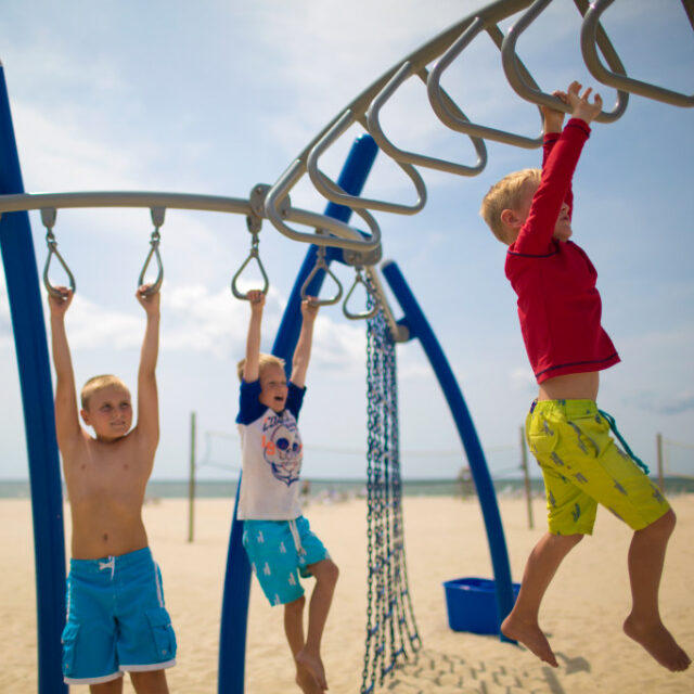 Kids playing at a playground on a beach.