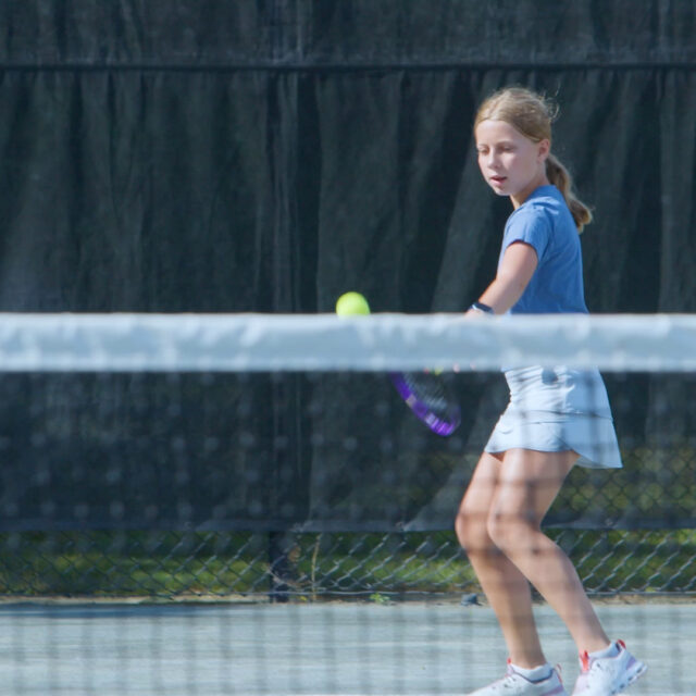girl returning tennis serve.